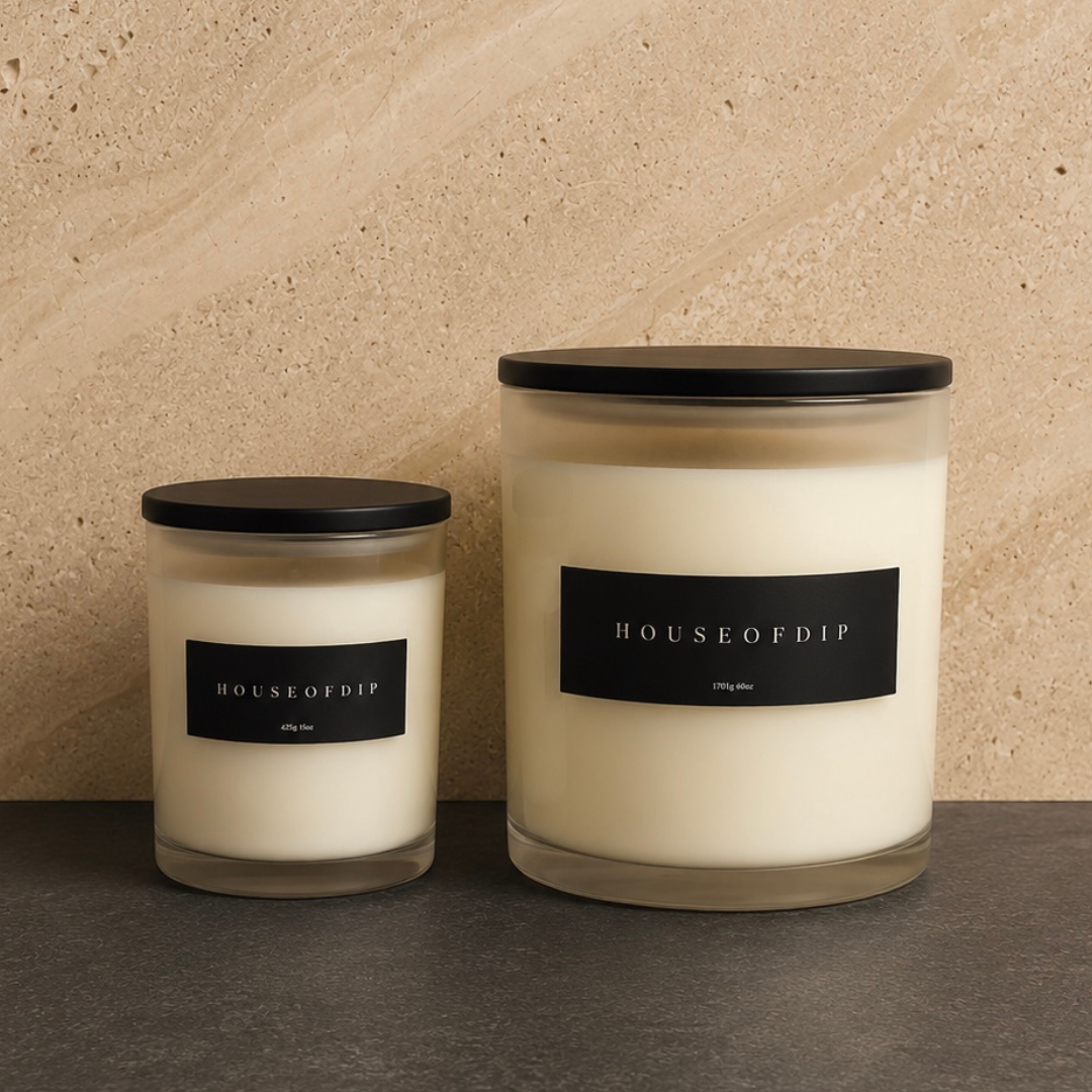 Two candles with black lids and labels on a neutral background